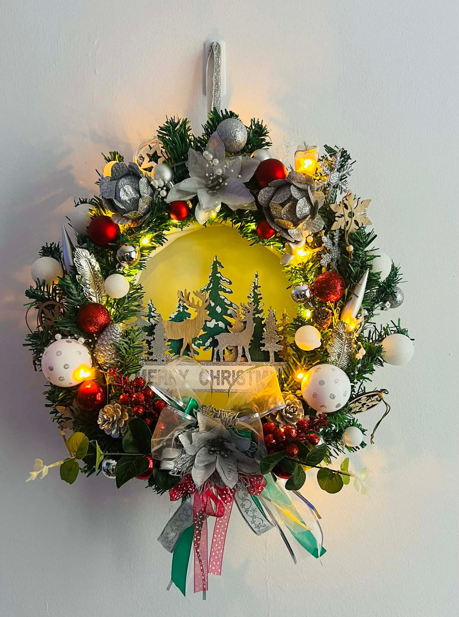 Kerstkrans met verlicht bostafereel, herten en ‘Merry Christmas’